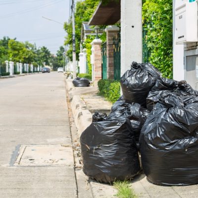 Trash bag ,black plastic garbage bags front of house.Rubbish pollution from consumption.